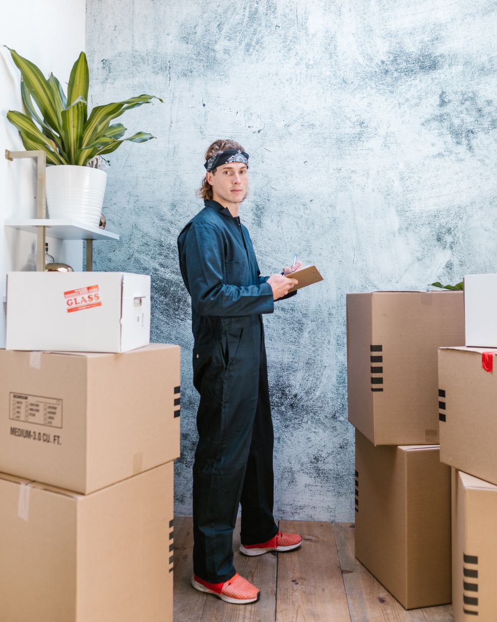 A mover in overalls with a checklist, standing beside stacked, labelled boxes